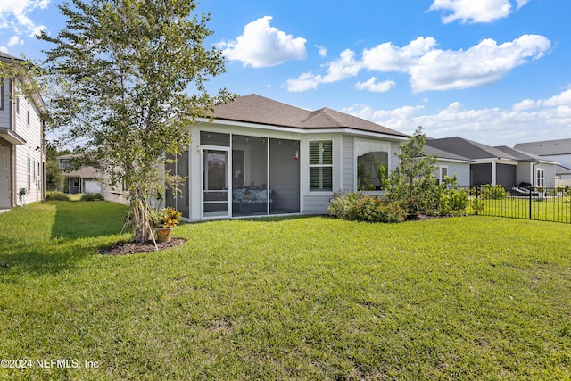 back of property with a sunroom, fence, and a yard