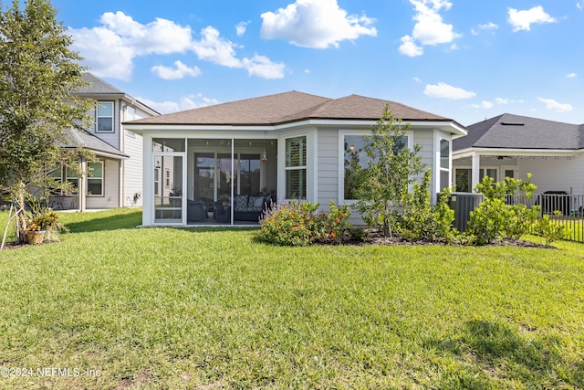 rear view of house with central air condition unit, a sunroom, and a lawn