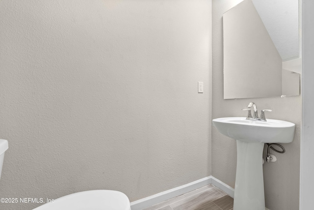 half bath featuring toilet, wood finished floors, and baseboards