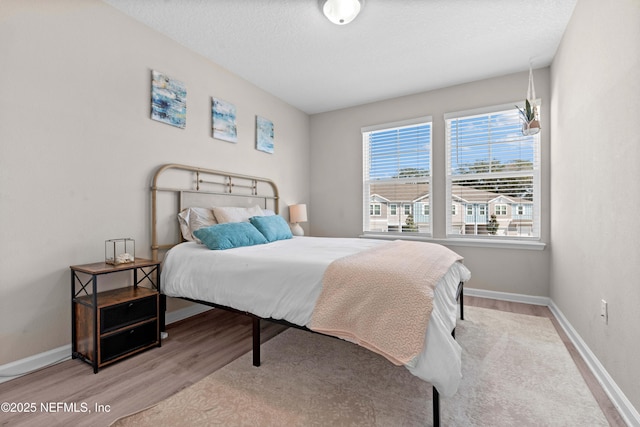 bedroom featuring a textured ceiling, baseboards, and wood finished floors