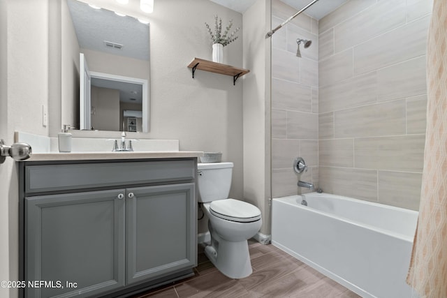 full bathroom with visible vents, toilet, shower / tub combination, wood finished floors, and vanity