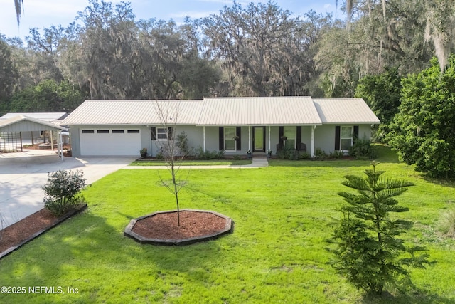 ranch-style house featuring metal roof, an attached garage, driveway, stucco siding, and a front yard