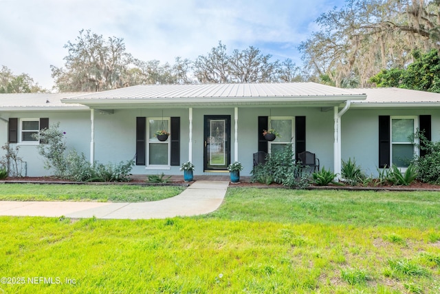 single story home with covered porch, a front yard, metal roof, and stucco siding