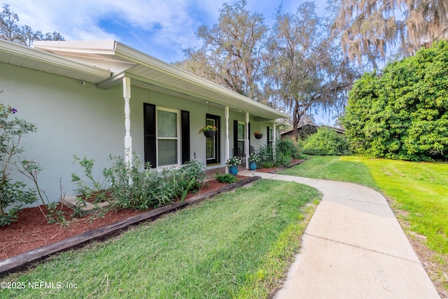 view of front of property featuring a porch, a front yard, and stucco siding