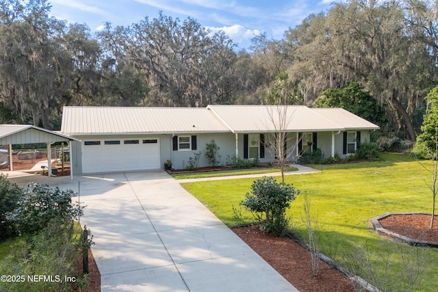 single story home with metal roof, an attached garage, concrete driveway, stucco siding, and a front yard