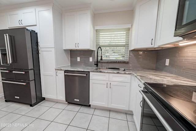 kitchen featuring light tile patterned floors, high end fridge, stainless steel dishwasher, white cabinets, and a sink