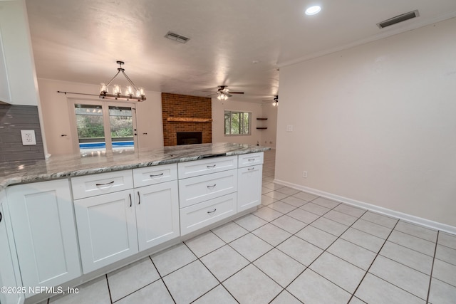 kitchen featuring white cabinets, visible vents, a peninsula, and open floor plan