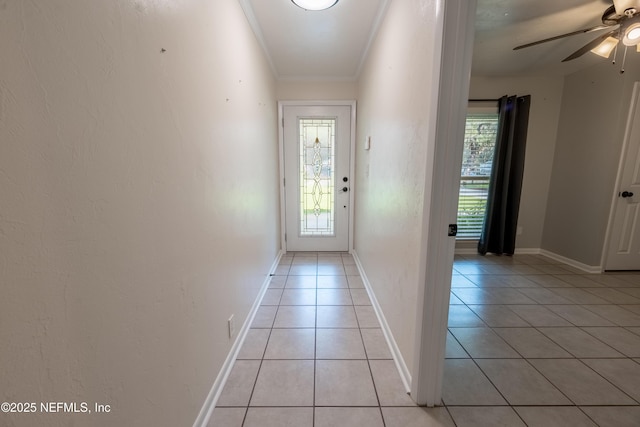 entryway with light tile patterned floors, ceiling fan, ornamental molding, and baseboards