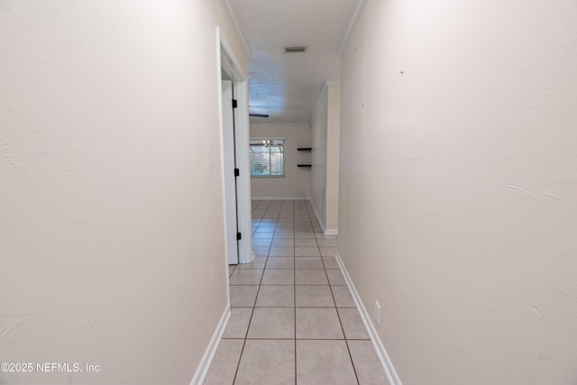 hall featuring light tile patterned flooring, crown molding, visible vents, and baseboards