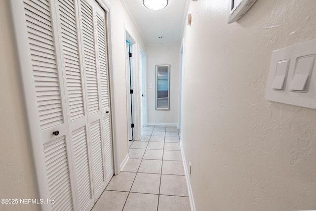 hallway featuring light tile patterned floors, baseboards, and ornamental molding