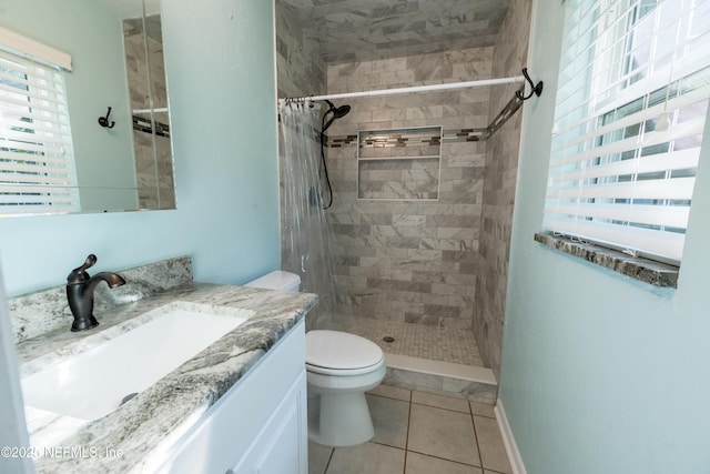 bathroom featuring toilet, tile patterned floors, tiled shower, and vanity