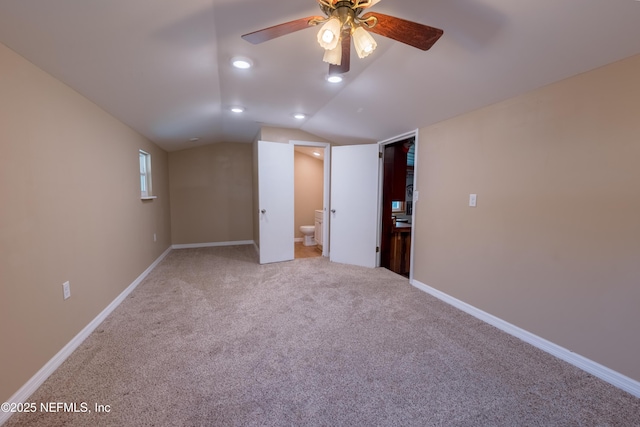 unfurnished bedroom featuring lofted ceiling, carpet floors, connected bathroom, and baseboards