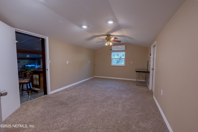 carpeted spare room with a ceiling fan, an AC wall unit, vaulted ceiling, and baseboards