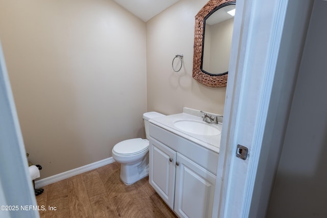 half bathroom featuring toilet, baseboards, and vanity