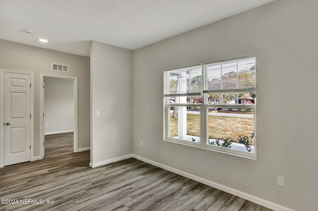 unfurnished room featuring wood finished floors, visible vents, and baseboards