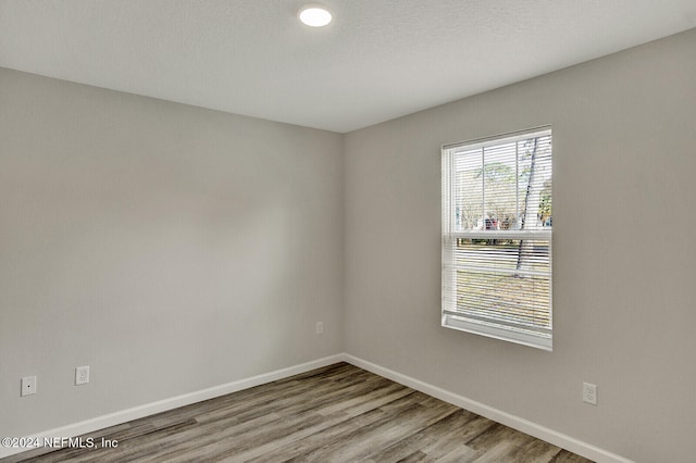 spare room with a textured ceiling, wood finished floors, and baseboards