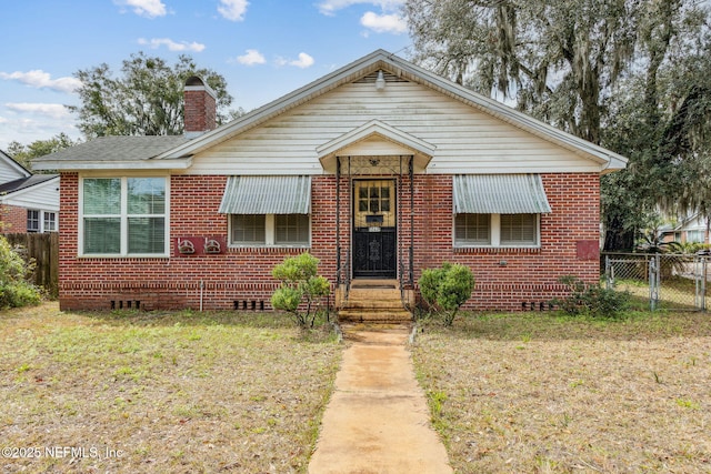 bungalow-style home featuring a chimney, crawl space, a gate, fence, and brick siding