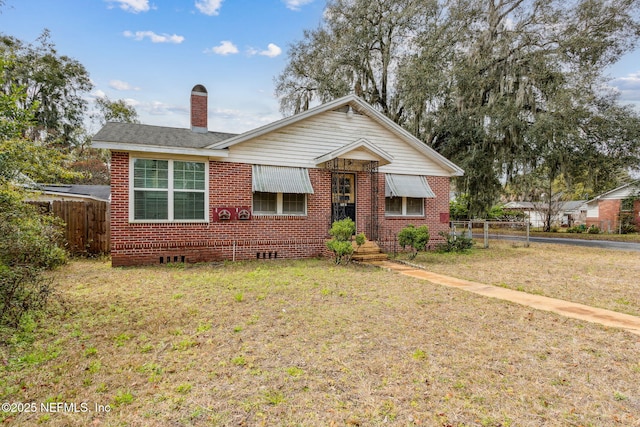 bungalow-style house with a front yard, crawl space, brick siding, and fence