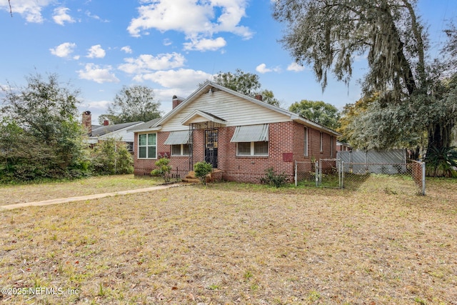 view of front of property featuring brick siding, a chimney, a gate, fence, and a front lawn