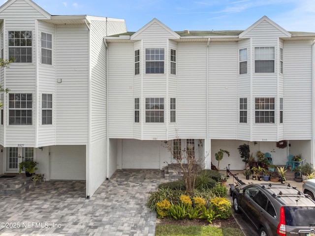 townhome / multi-family property with decorative driveway, french doors, and an attached garage