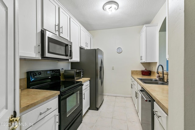 kitchen with a toaster, white cabinets, appliances with stainless steel finishes, a textured ceiling, and a sink