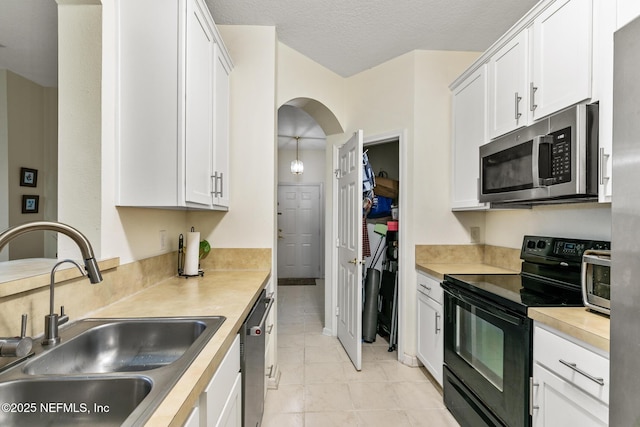 kitchen with appliances with stainless steel finishes, light countertops, a sink, and white cabinetry