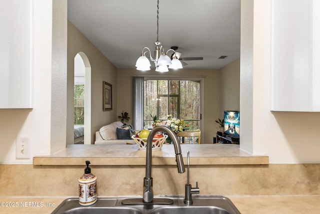 kitchen with visible vents, arched walkways, open floor plan, hanging light fixtures, and a sink