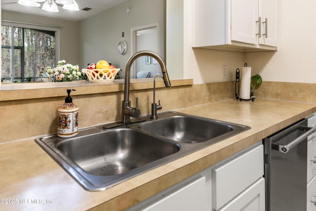 kitchen with light countertops, visible vents, stainless steel dishwasher, white cabinets, and a sink