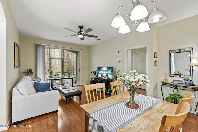 dining room with visible vents, wood finished floors, and ceiling fan with notable chandelier