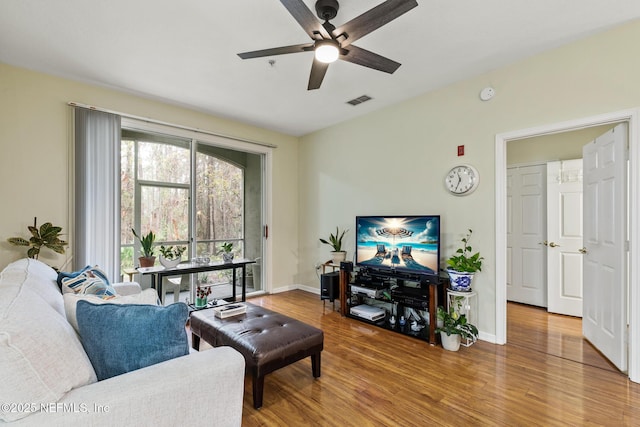 living room featuring visible vents, ceiling fan, baseboards, and wood finished floors