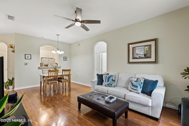 living area with hardwood / wood-style flooring, visible vents, arched walkways, and baseboards