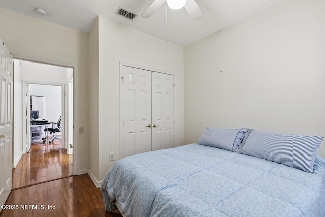 bedroom featuring wood finished floors, visible vents, baseboards, a ceiling fan, and a closet