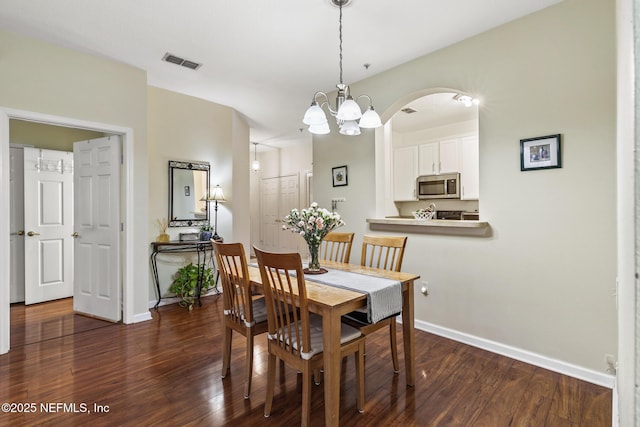 dining area featuring a notable chandelier, dark wood-style flooring, visible vents, and baseboards