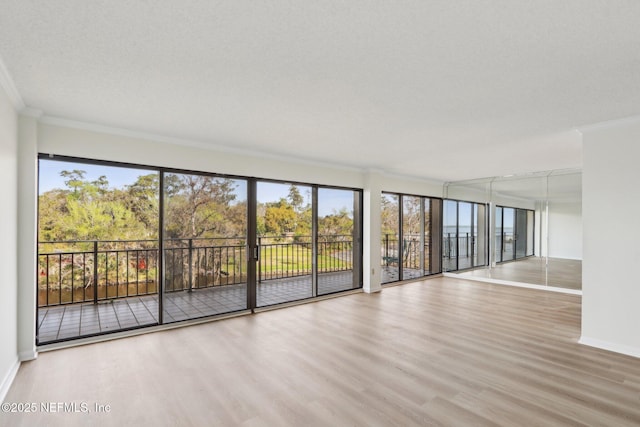 spare room featuring ornamental molding, baseboards, and wood finished floors