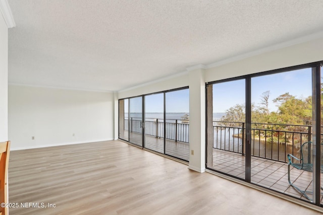 unfurnished room with a textured ceiling, baseboards, and wood finished floors