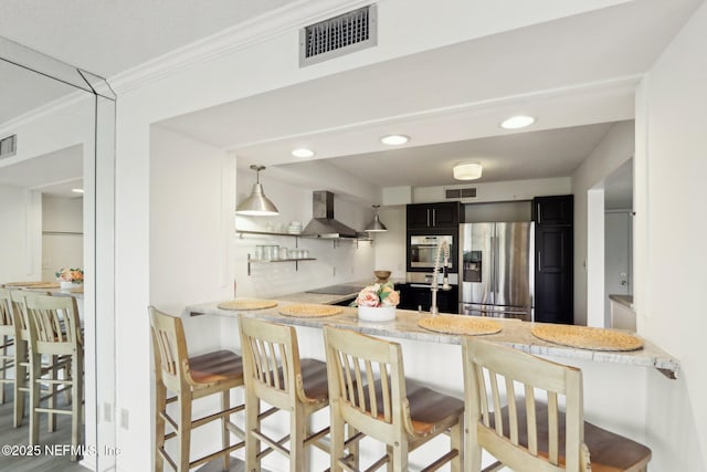 kitchen with black electric stovetop, visible vents, wall chimney range hood, and stainless steel fridge with ice dispenser