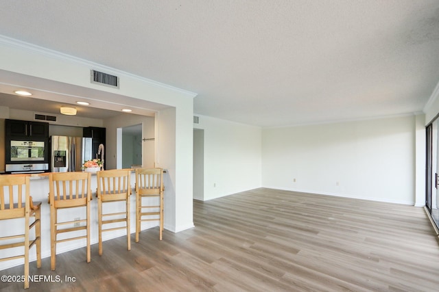 interior space featuring baseboards, light wood-style flooring, visible vents, and crown molding