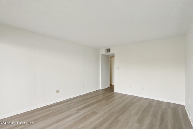 empty room featuring baseboards, visible vents, and wood finished floors