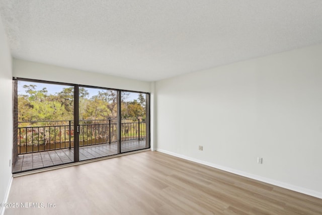 spare room with a textured ceiling, baseboards, and wood finished floors