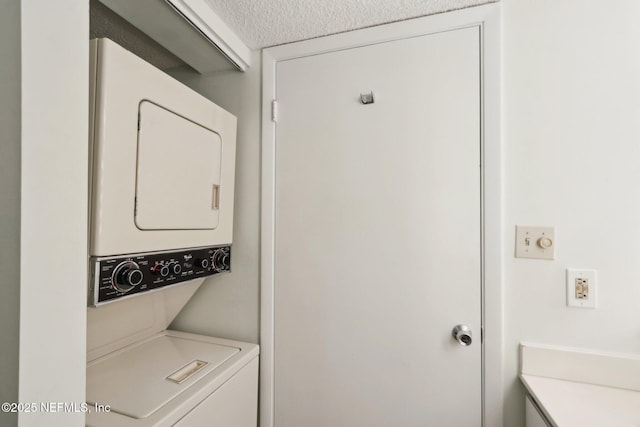 laundry room featuring stacked washer / dryer, laundry area, and a textured ceiling