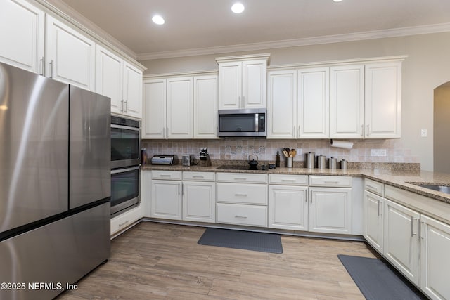 kitchen with appliances with stainless steel finishes, ornamental molding, and tasteful backsplash