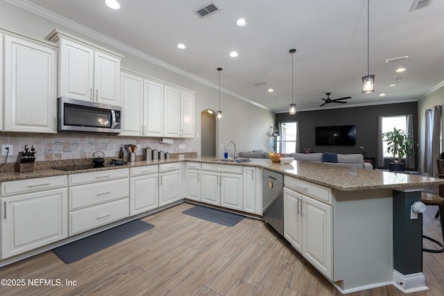 kitchen featuring visible vents, appliances with stainless steel finishes, open floor plan, a peninsula, and a sink