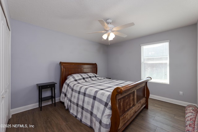 bedroom featuring dark wood-style floors, ceiling fan, a closet, and baseboards