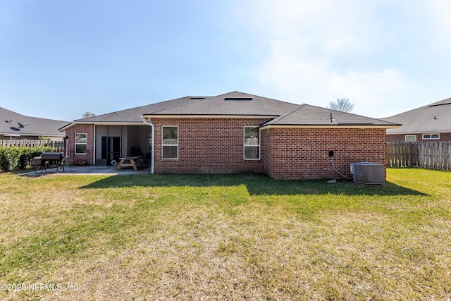 back of house featuring central AC unit, a lawn, fence private yard, a patio area, and brick siding