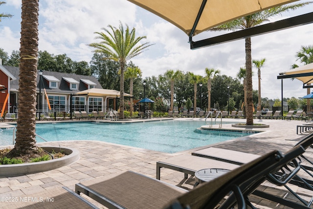 community pool with a patio area and fence