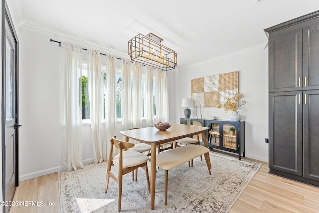 dining space featuring ornamental molding, light wood-type flooring, a chandelier, and baseboards