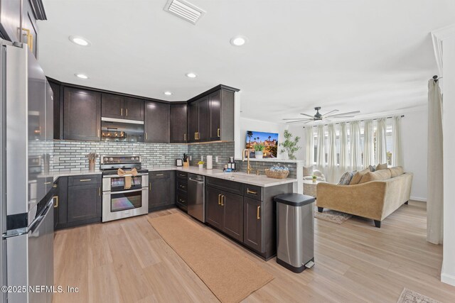 kitchen featuring stainless steel appliances, tasteful backsplash, visible vents, a sink, and dark brown cabinetry