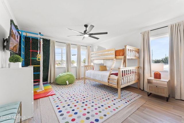 bedroom featuring multiple windows, crown molding, and wood finished floors