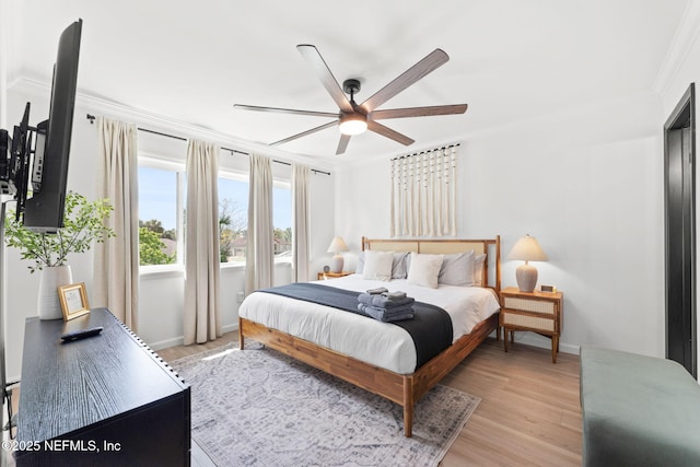 bedroom featuring baseboards, ornamental molding, a ceiling fan, and light wood-style floors