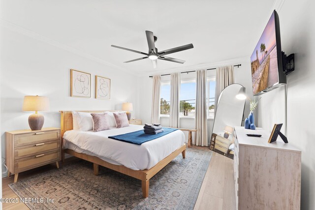 bedroom featuring light wood-style floors, crown molding, and a ceiling fan